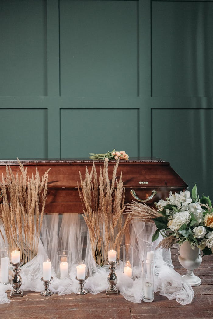 A serene funeral scene with lit candles, floral arrangements, and a coffin, creating a peaceful ambiance.
